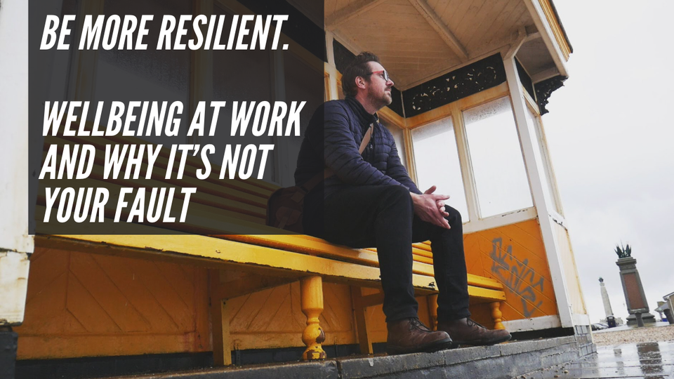 A photo of Rob Lambert sat on a seaside bench with the words "be more resilient" overlayed