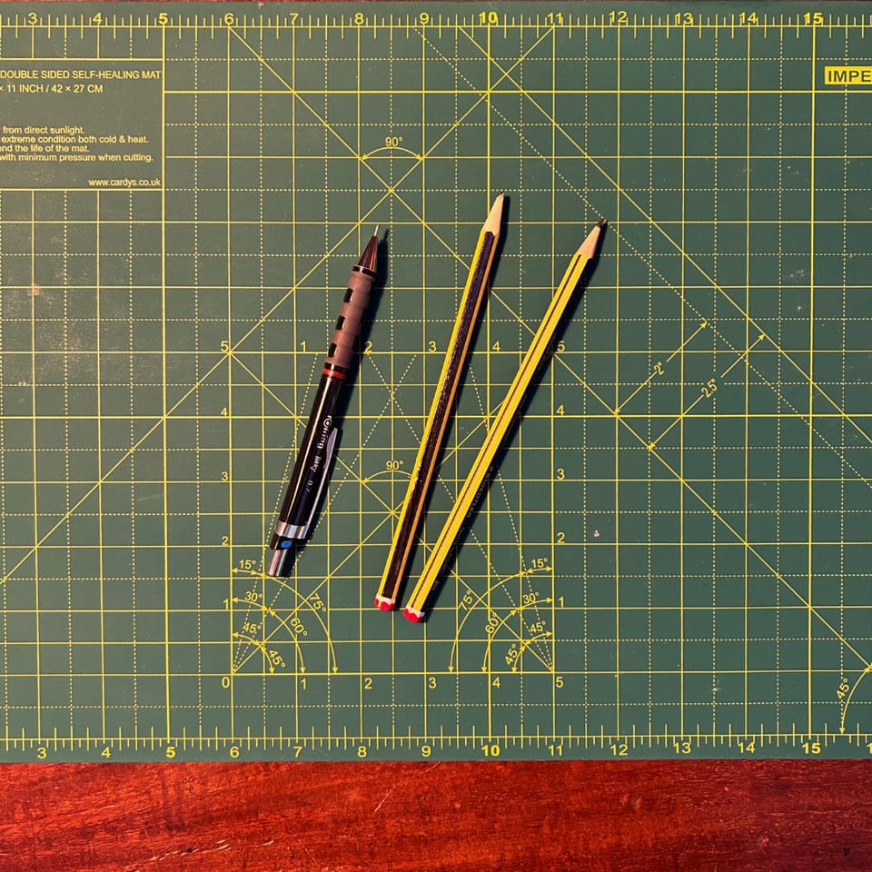 An image of pens and pencils on a cutting board