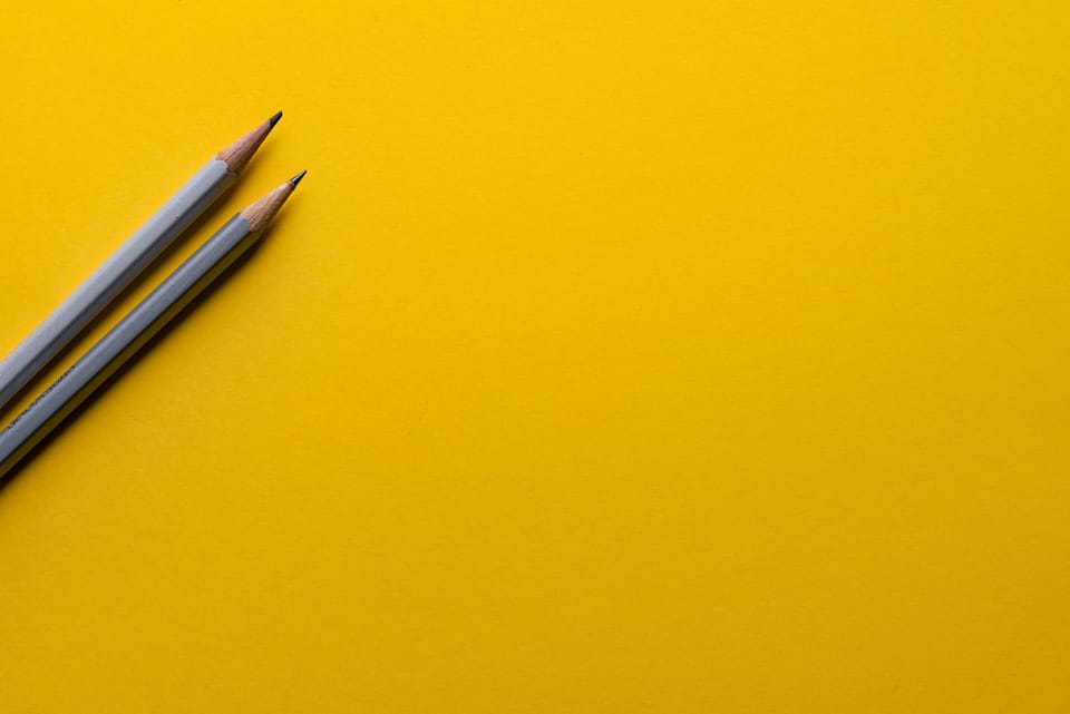 An image of some pencils laid down on a yellow backgrouns