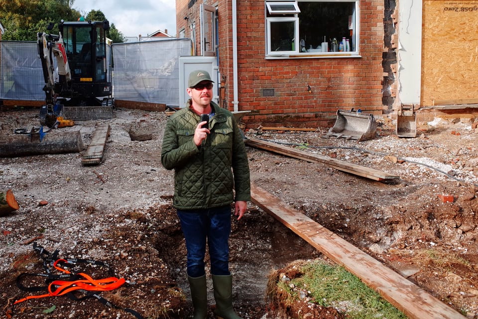 Rob Lambert stood in a garden trench recording a podcast